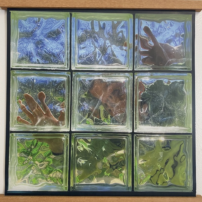 Nine panel glass block with sky, hands, and greenery